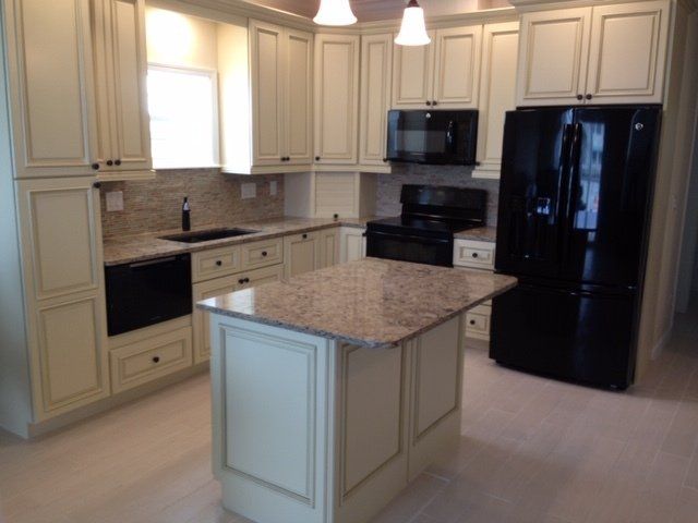 A kitchen with white cabinets and a black refrigerator