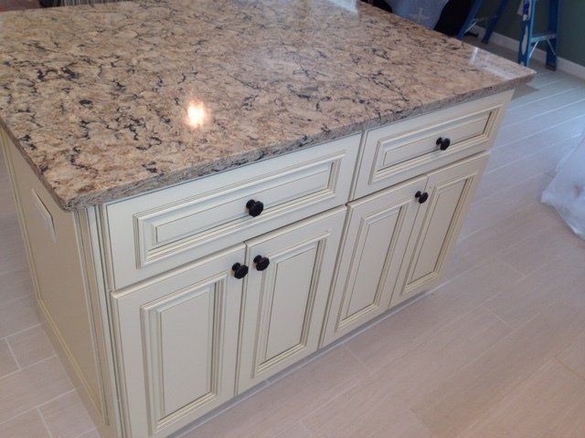 A kitchen island with granite counter tops and white cabinets.
