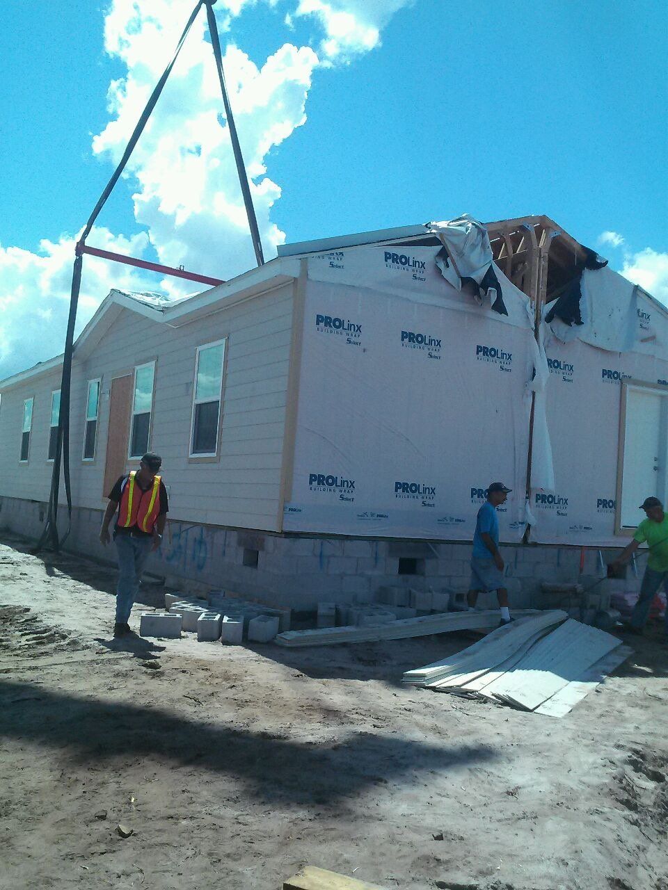 A man in a yellow vest is standing in front of a mobile home being built