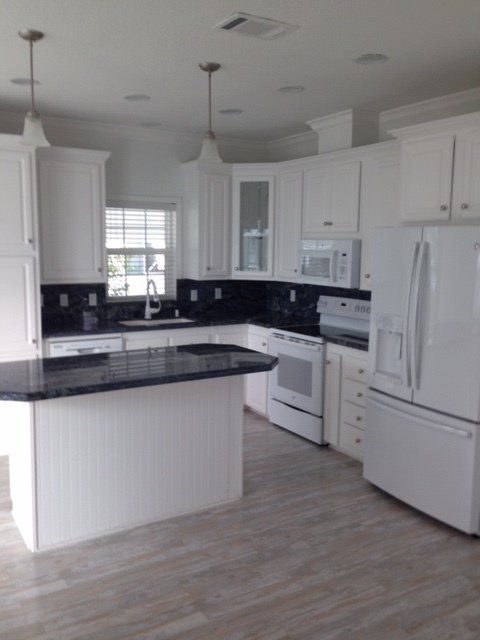A kitchen with white cabinets and black counter tops
