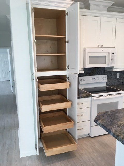 A kitchen with white cabinets and wooden drawers