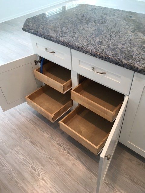 A kitchen cabinet with drawers pulled out of it