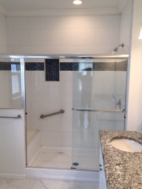 A bathroom with a walk in shower and a sink