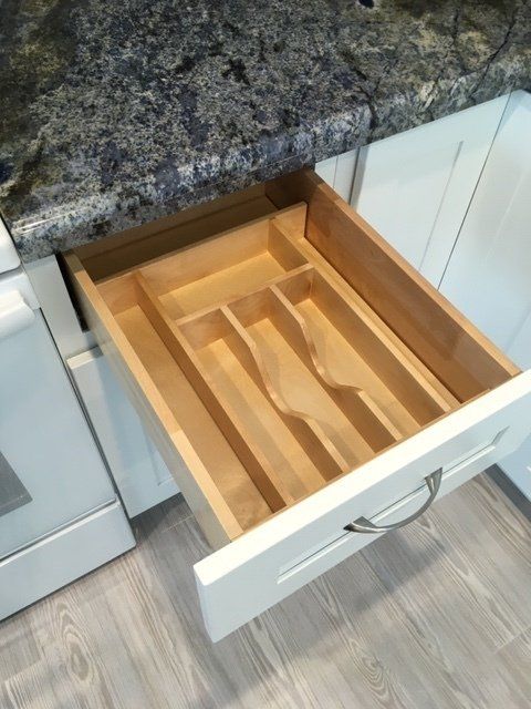 A kitchen drawer with a wooden cutlery tray in it