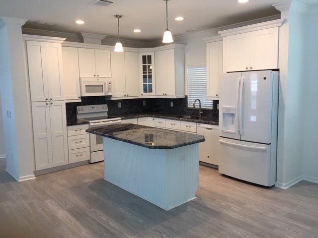 A kitchen with white cabinets and black granite counter tops