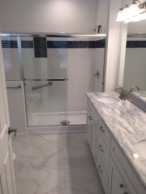 A bathroom with two sinks , a shower and a mirror.