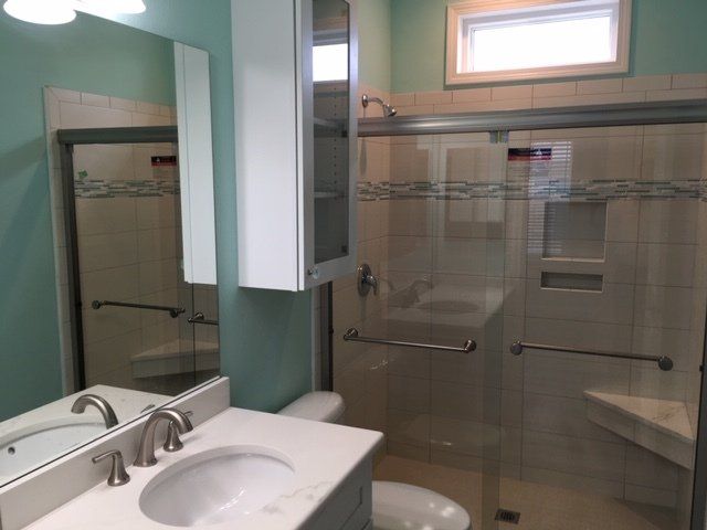 A bathroom with a sink toilet and shower with sliding glass doors