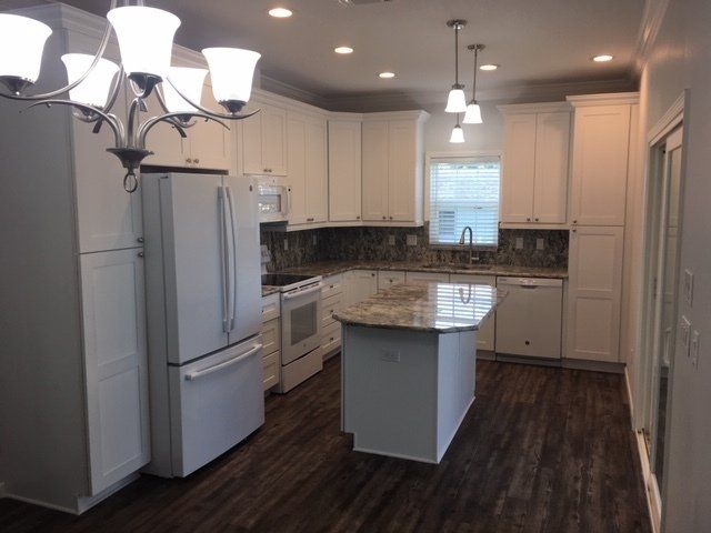 A kitchen with white cabinets and a large island