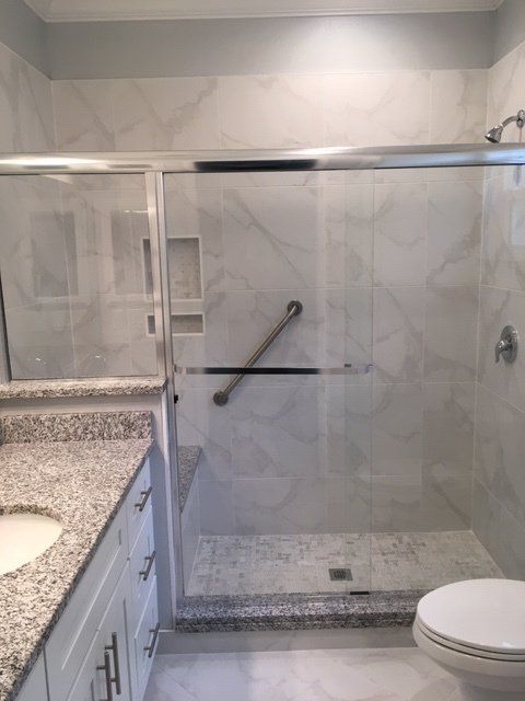 A bathroom with a walk in shower , toilet , sink and mirror.