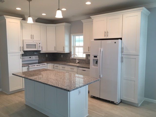 A kitchen with white cabinets and granite counter tops