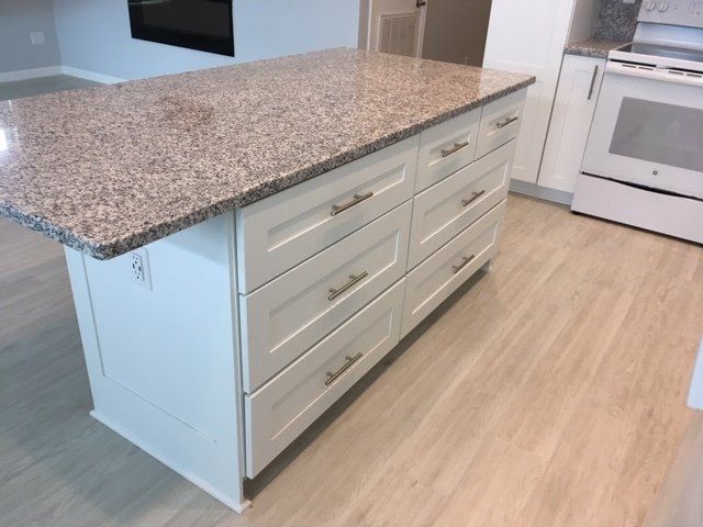 A kitchen with granite counter tops and white cabinets