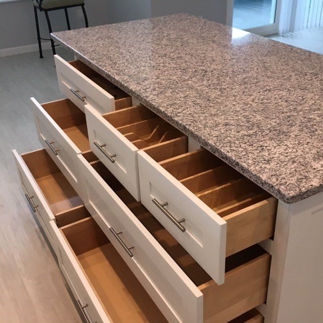 A kitchen island with drawers open and a granite counter top