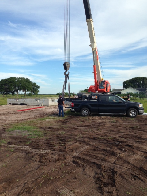 A truck is being lifted by a crane in a dirt field