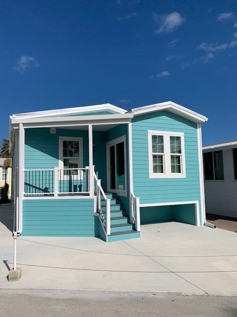 A blue and white mobile home with a porch and stairs