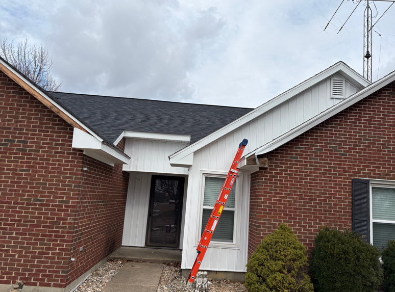 Front entrance of a brick house with a red ladder leaning against the roofline
