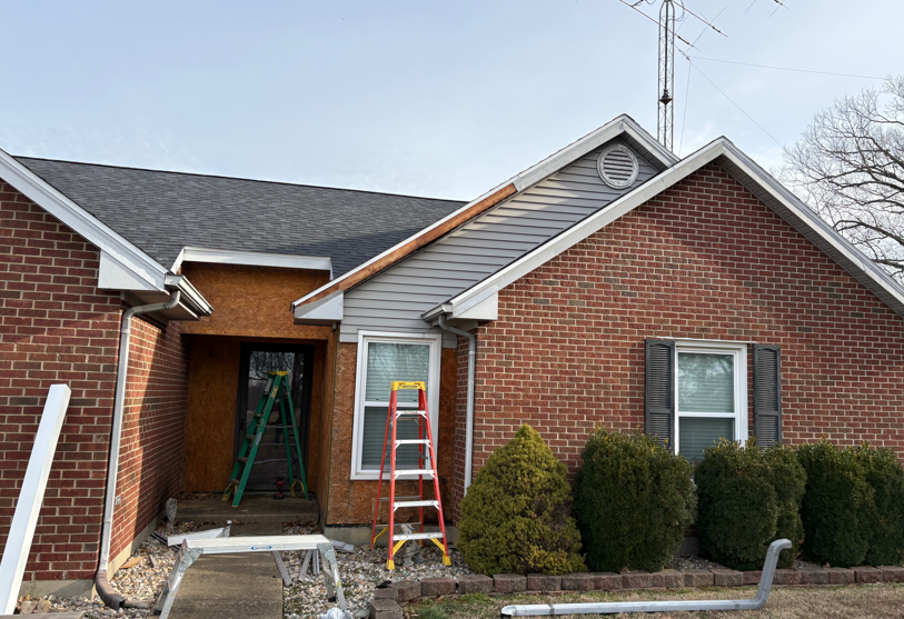 Brick house exterior with a ladder and ladder stand at the front entrance under renovation