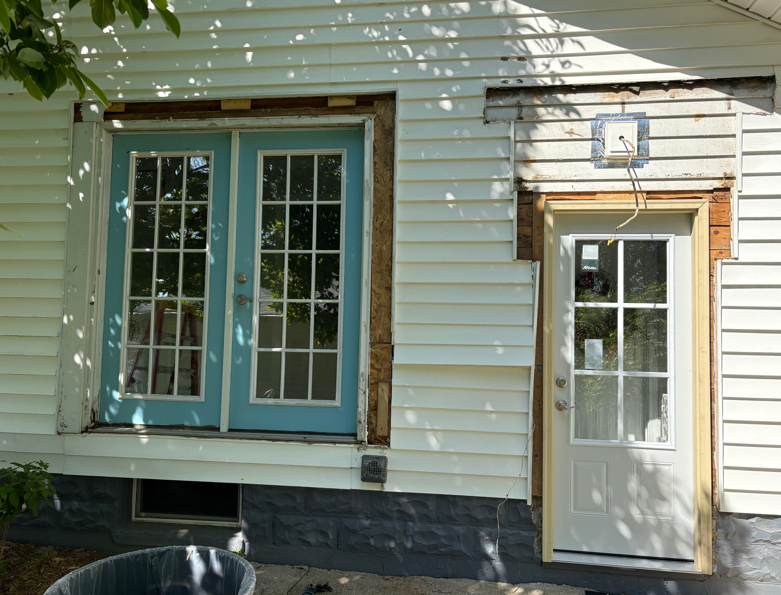 House exterior with blue double doors and a white side door under a small awning