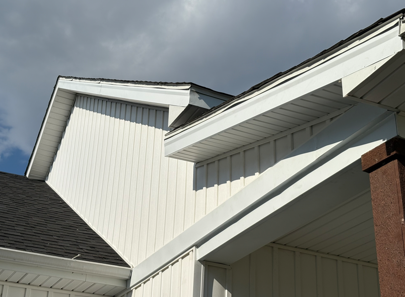 Close-up of white house rooflines and eaves against a blue sky