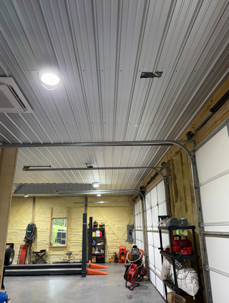 Garage interior with tools, shelves, and a red lawnmower under a corrugated ceiling