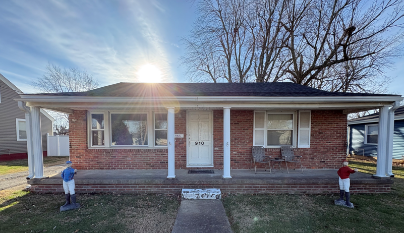 Brick ranch house with white trim and front porch, two holiday decorations on the walkway.