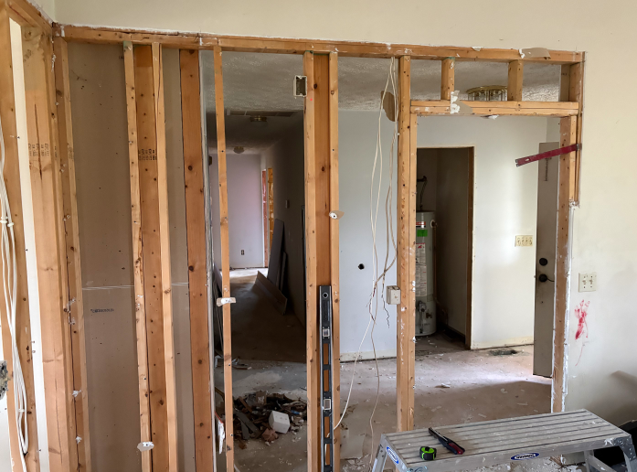 Unfinished interior wall framing in a house under renovation, with door openings and exposed studs.