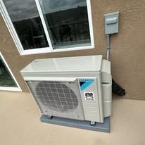 Outdoor air conditioning unit mounted on a wall, near a window.