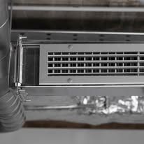 Silver air vent in ceiling, connected to ductwork.