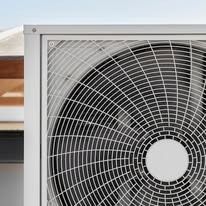 Close-up of a white air conditioning unit with a circular fan and a protective grill.