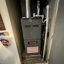 A furnace in a closet with a metal body and attached pipes.