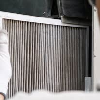 Close-up of a dirty air filter in an HVAC system, showing vertical pleated filter.