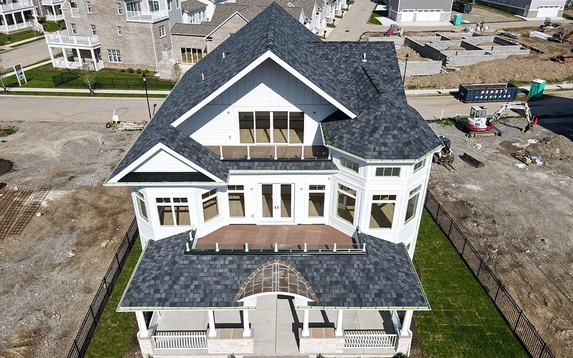 An aerial view of a large house under construction in a residential area.