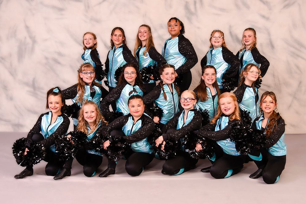 A group of young female cheerleaders posing in matching teal and black uniforms, holding black pom-poms. They are smiling in a studio setting.