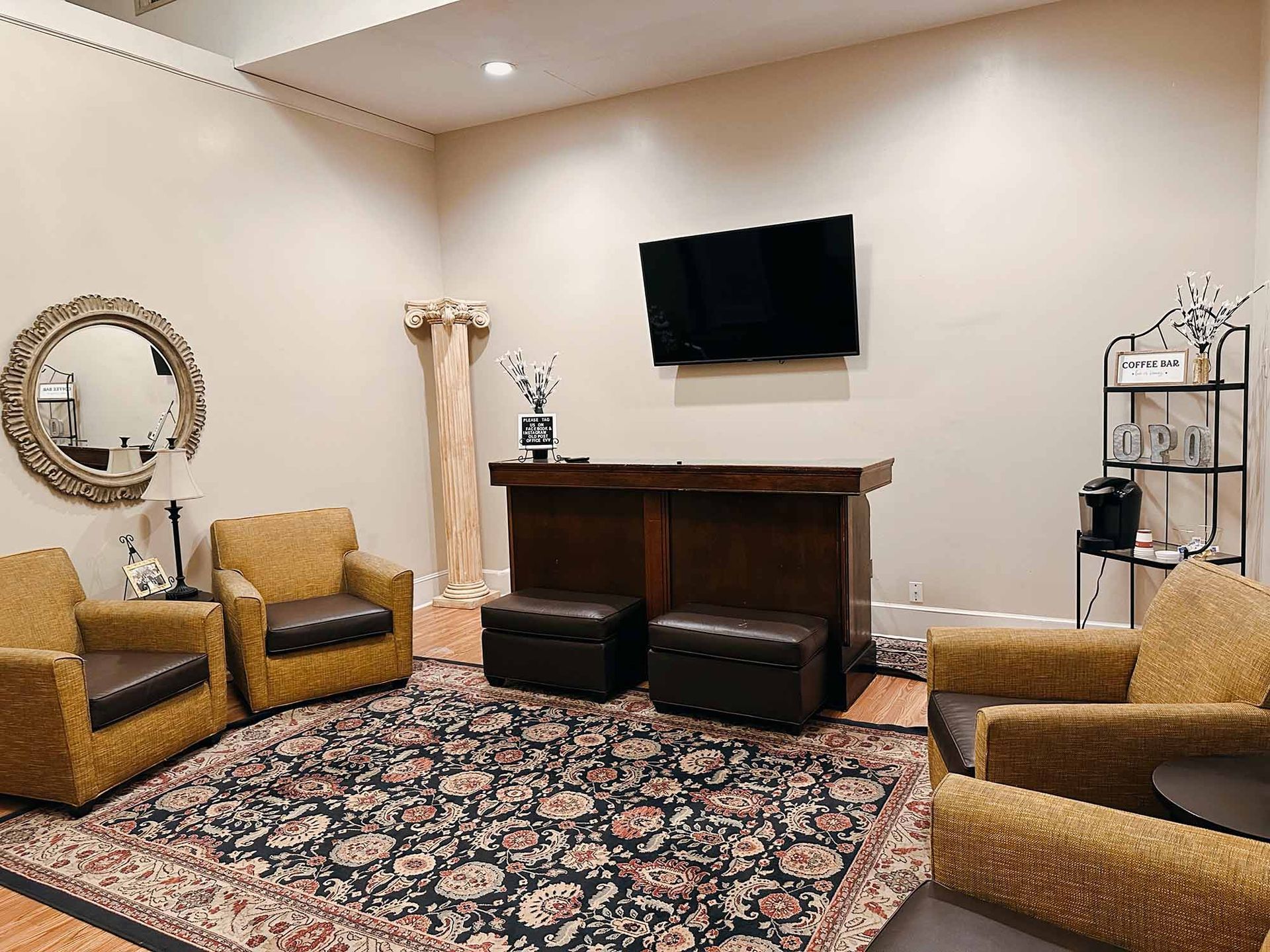 A living room with chairs and a flat screen tv on the wall.