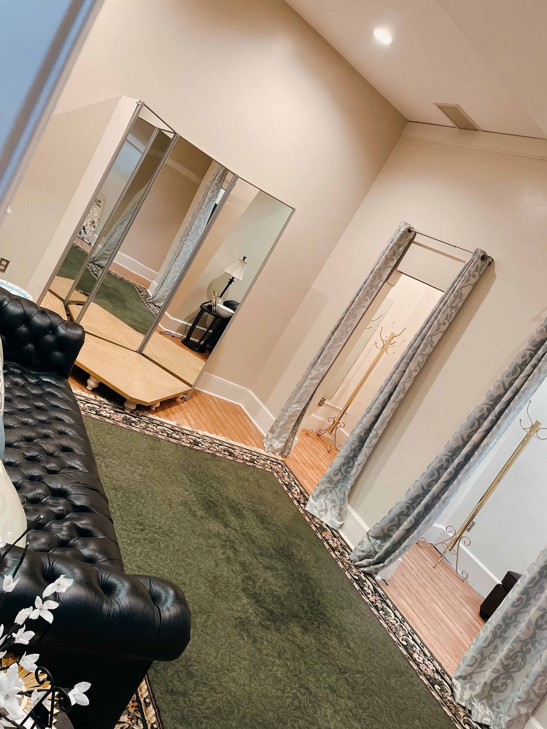 A dressing room with a black couch and a leopard print rug