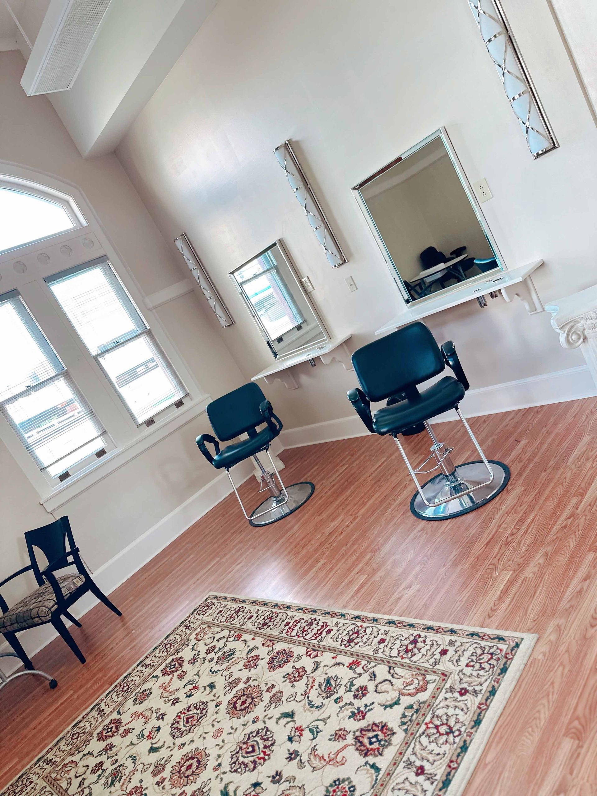 A room with three chairs and a rug on the floor