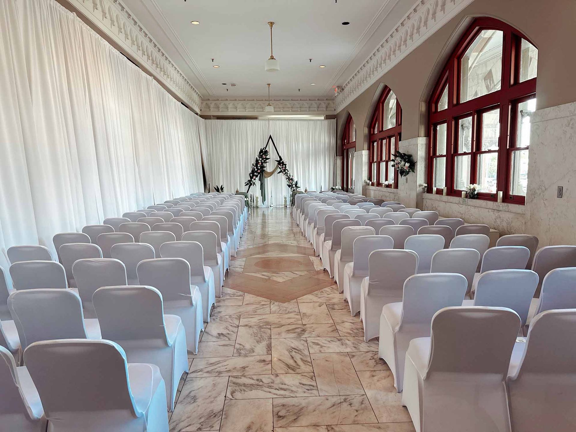 Rows of white chairs are lined up in a long room.