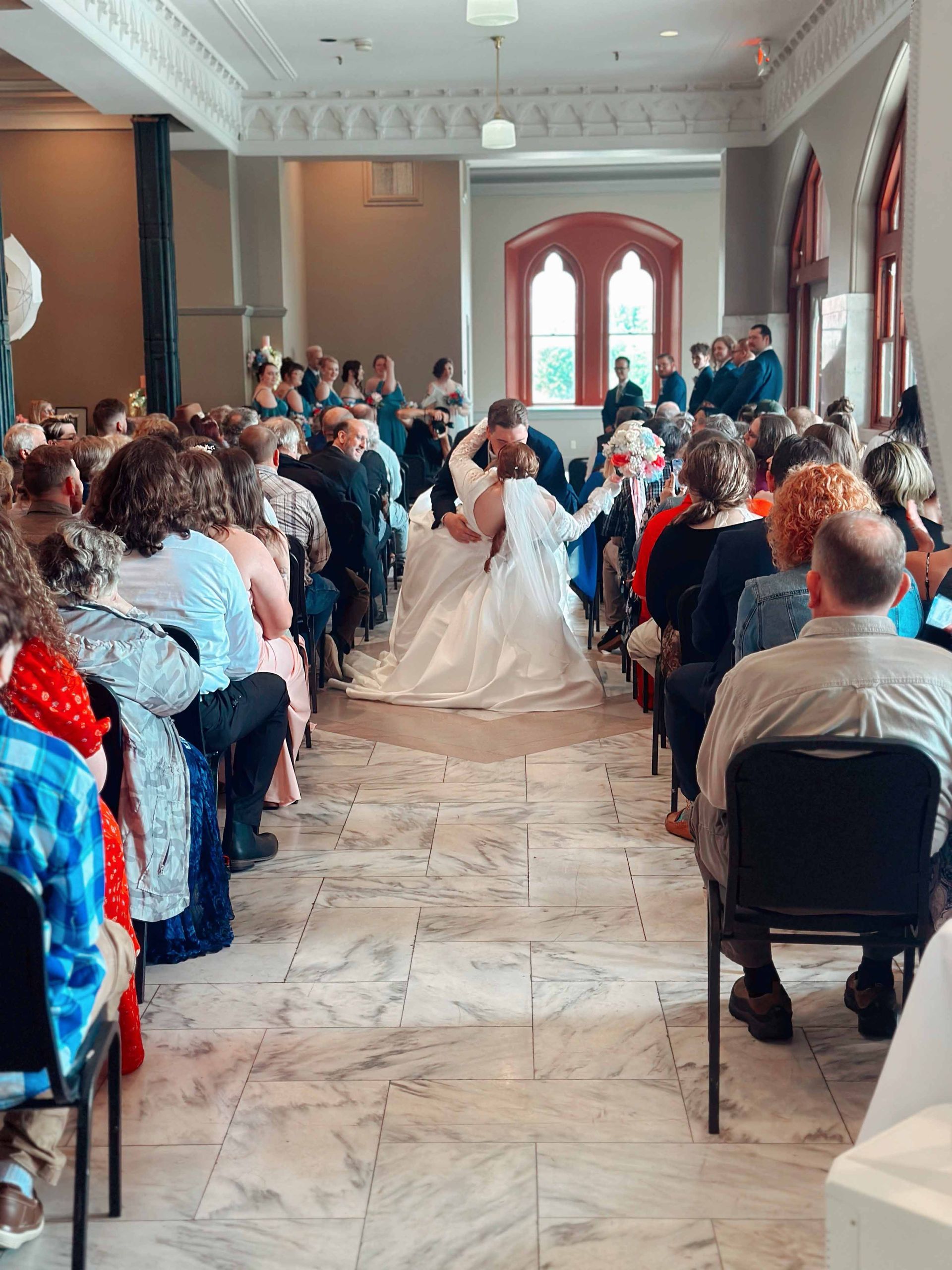 A large group of people are sitting in chairs watching a wedding ceremony.