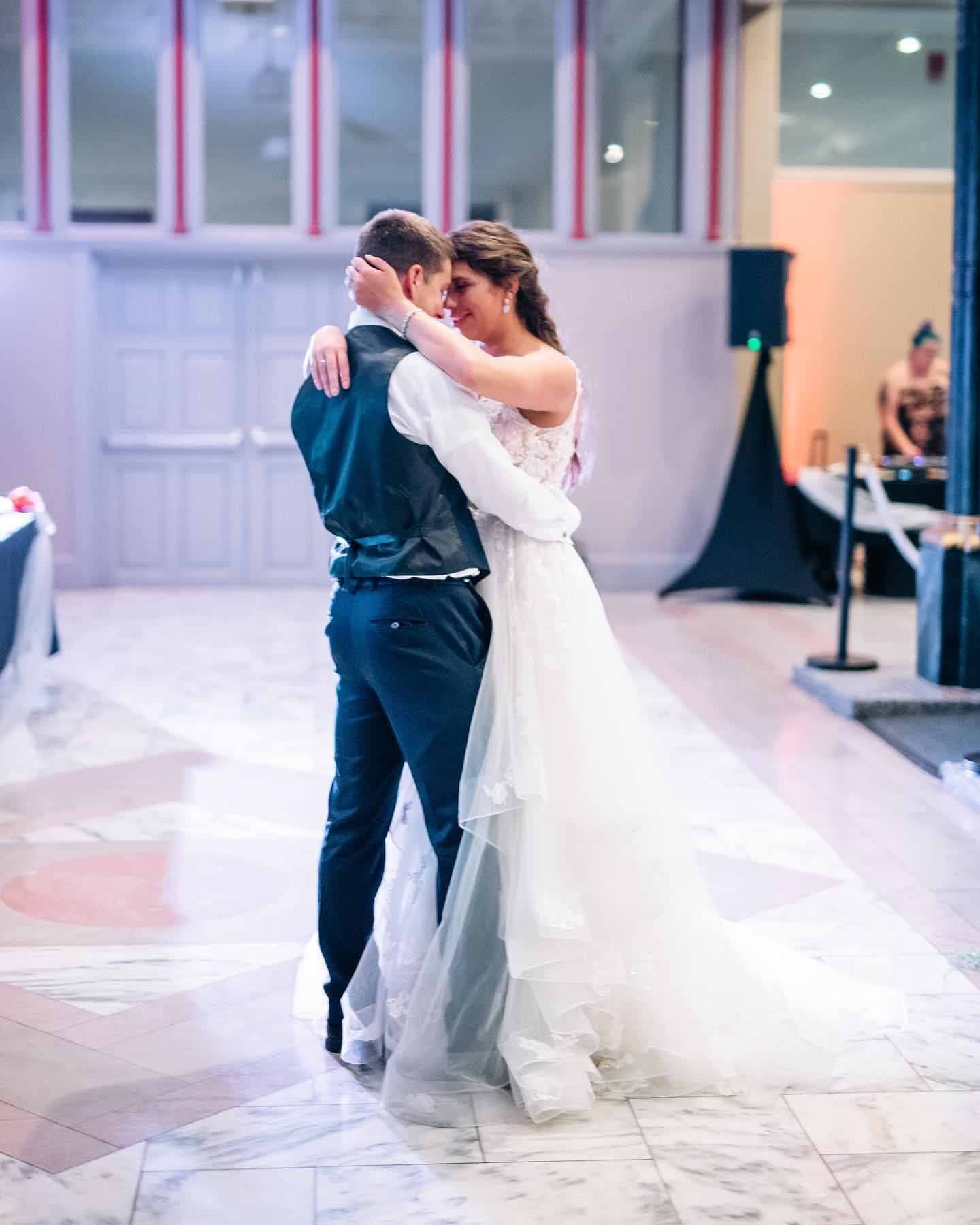 A bride and groom are dancing together at their wedding reception.