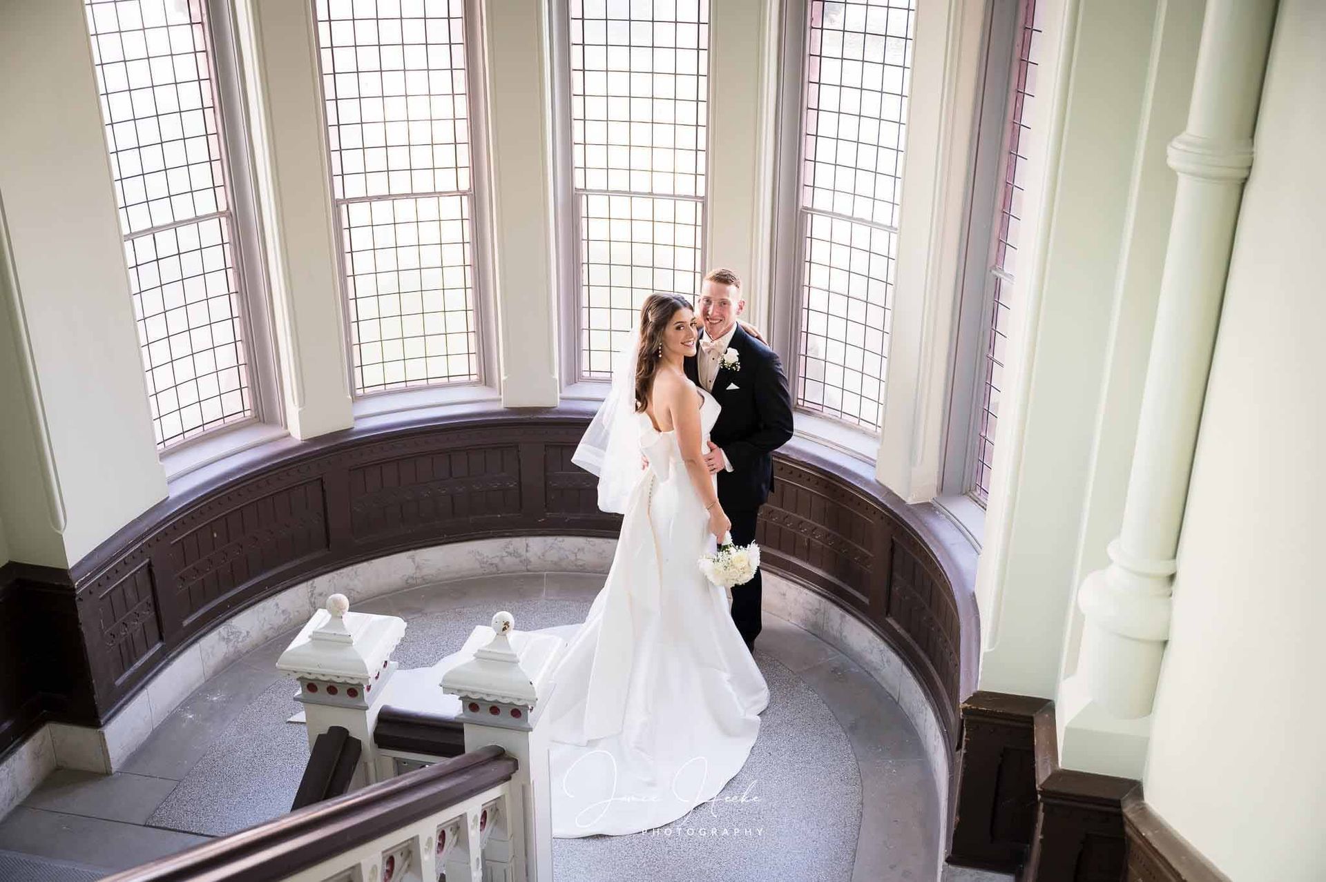 A bride and groom are posing for a picture on the stairs of a building.