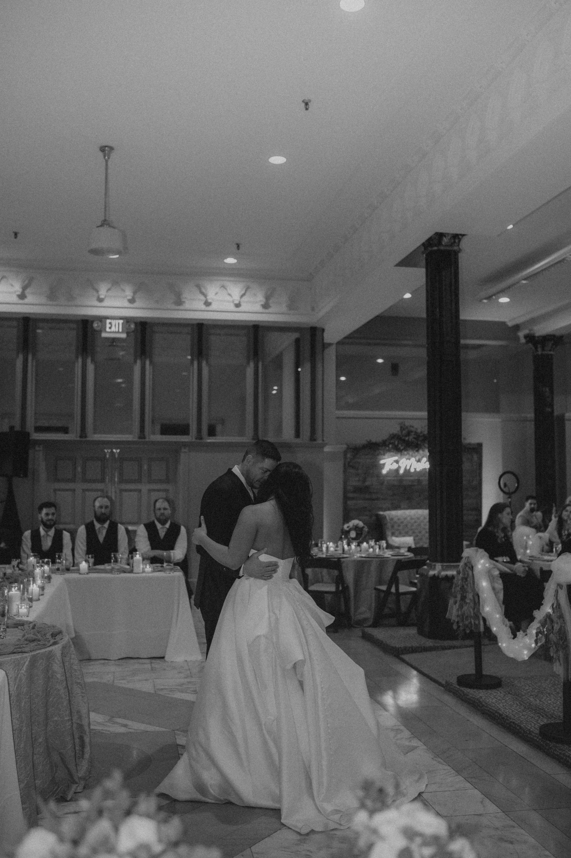 A black and white photo of a bride and groom dancing at their wedding reception.