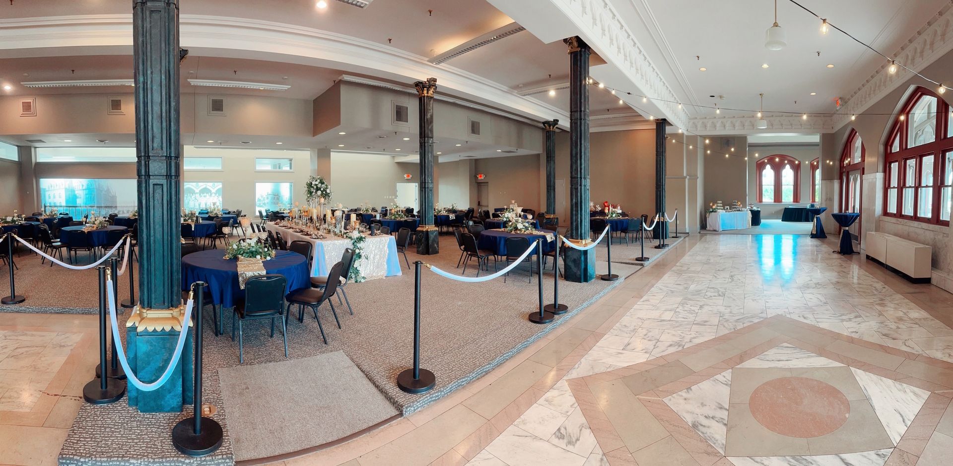 A large room with tables and chairs set up for a wedding reception.