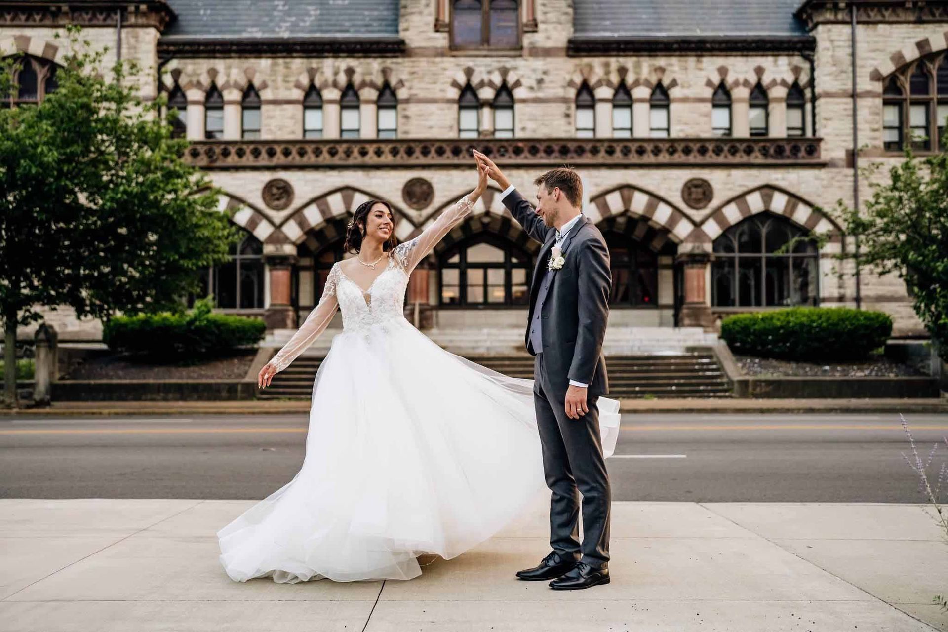 A bride and groom are dancing in front of a building.