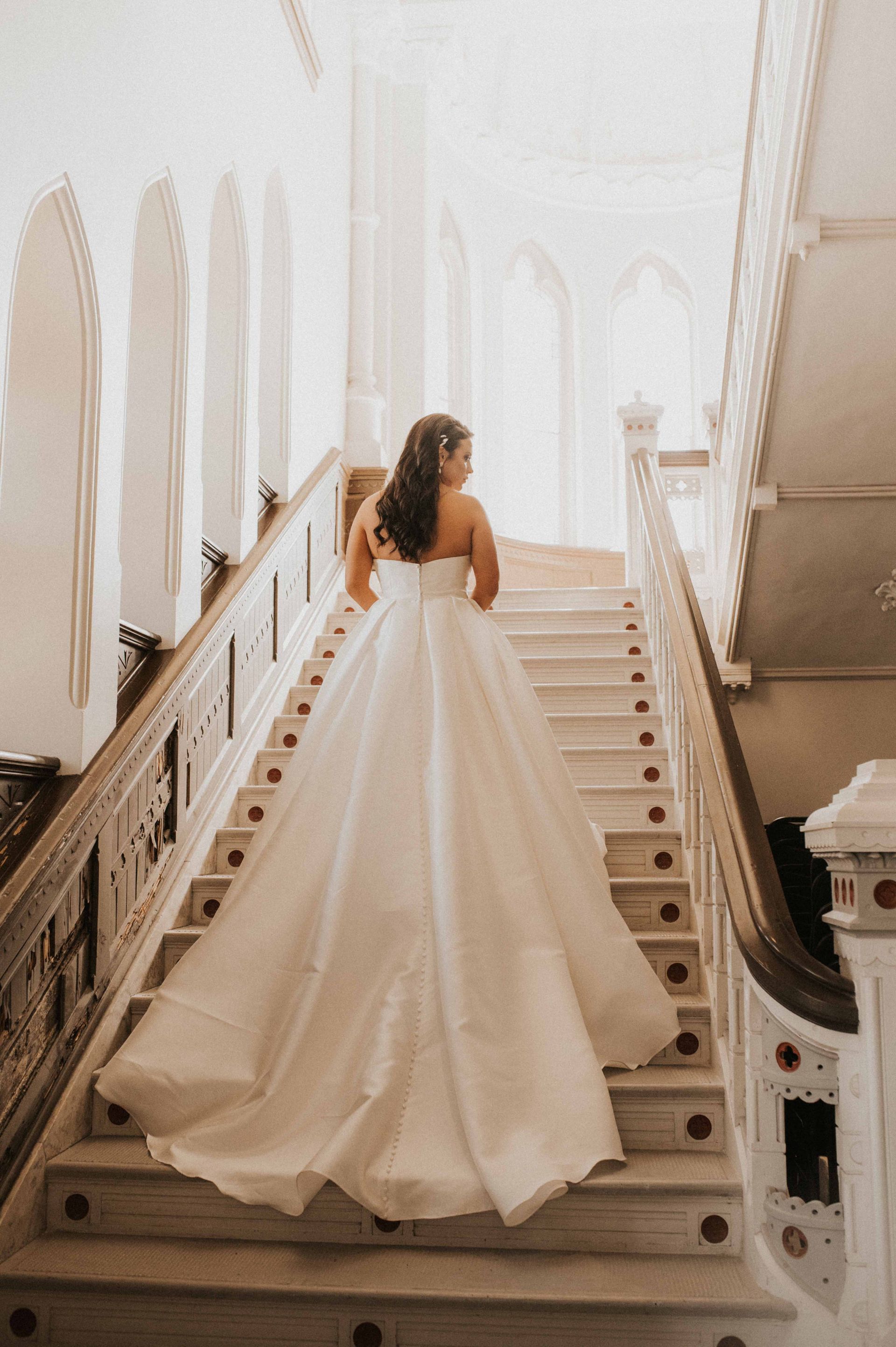 A woman in a wedding dress is walking down a set of stairs.