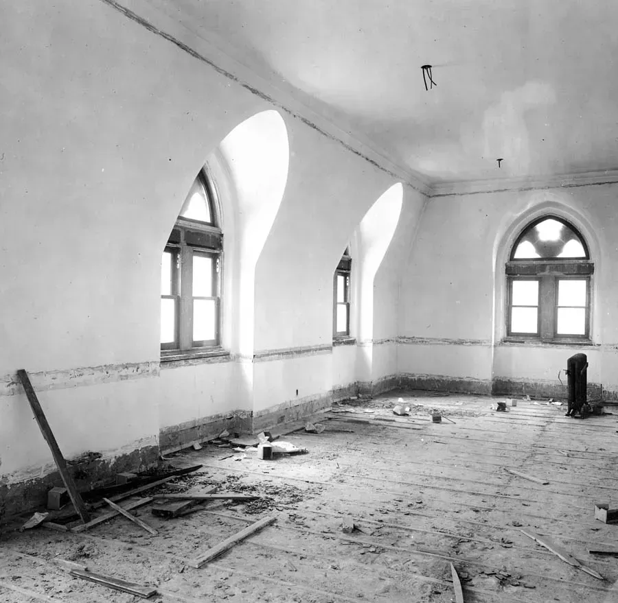 A black and white photo of an empty room with arched windows