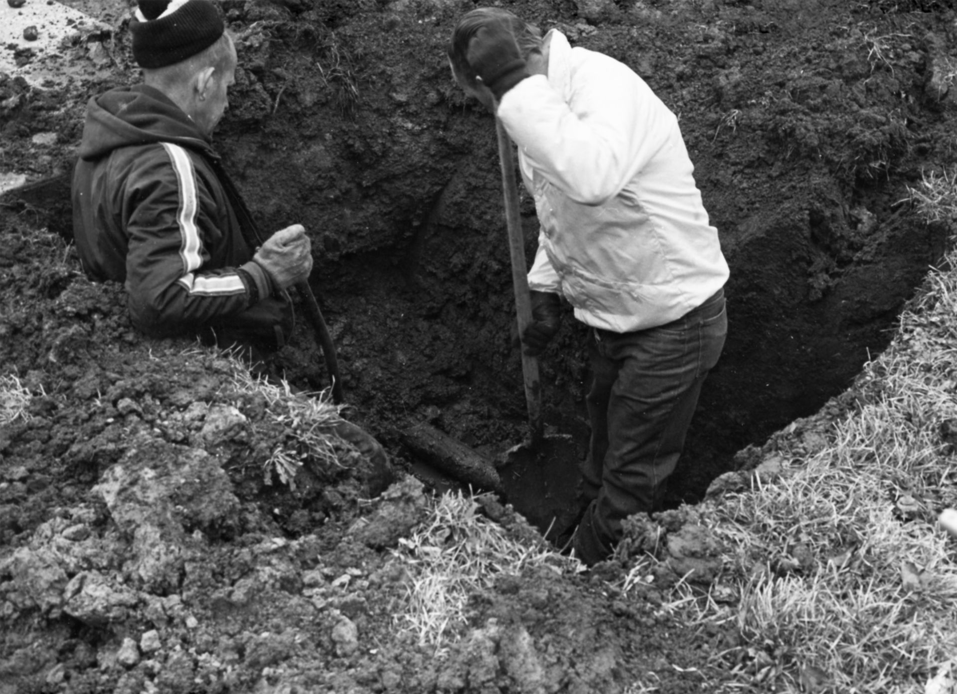 Two men are digging in the dirt with shovels