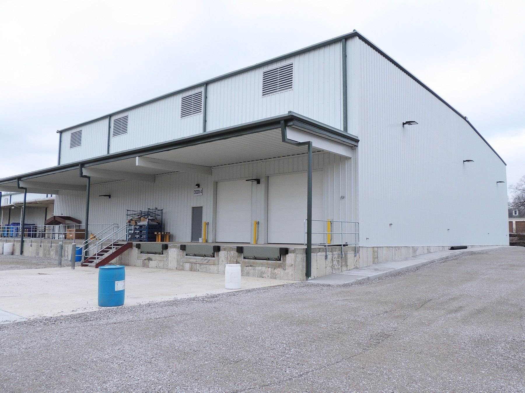 A large white building with a blue trash can in front of it