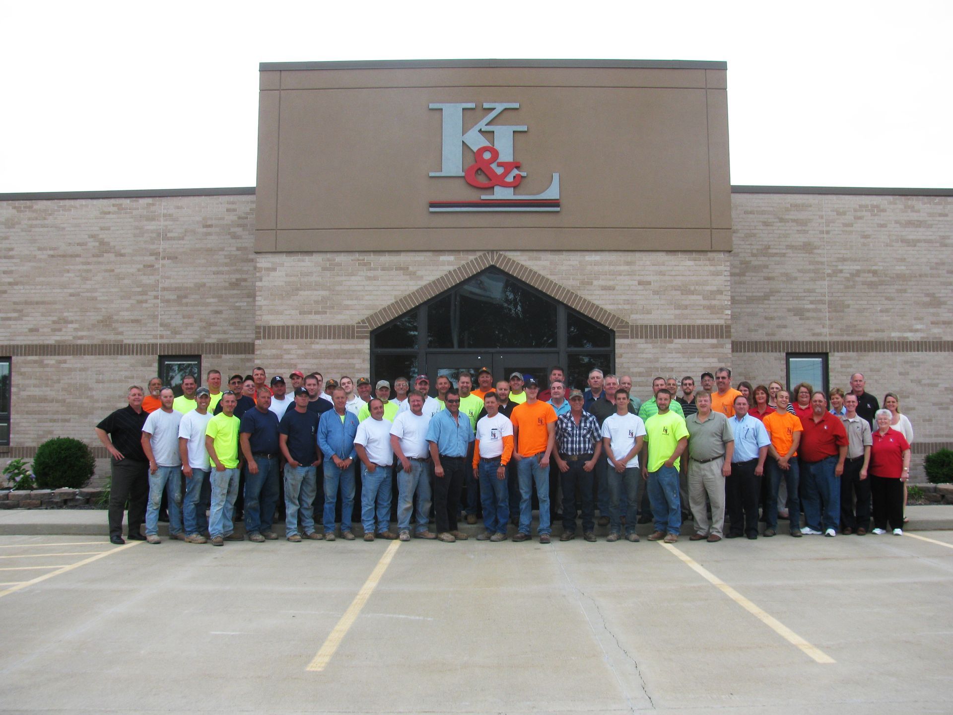 A group of people standing in front of a building with the letter k on it