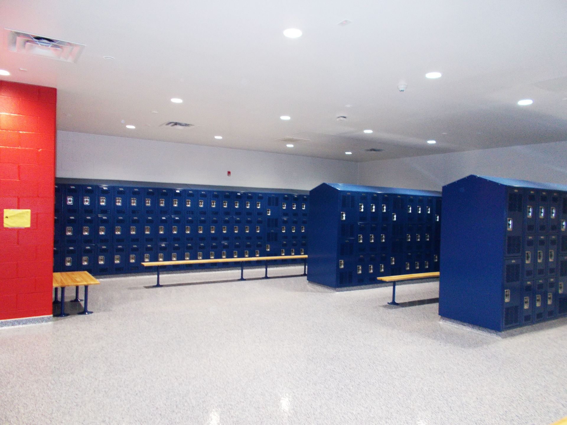A locker room with lots of blue lockers and benches