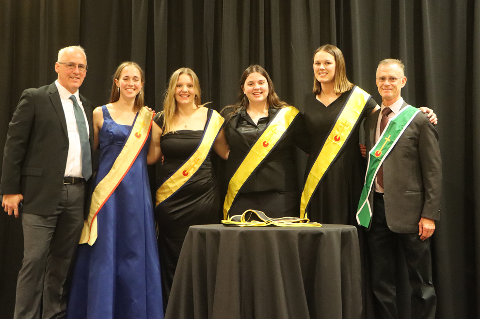 A group of people are posing for a picture in front of a table.