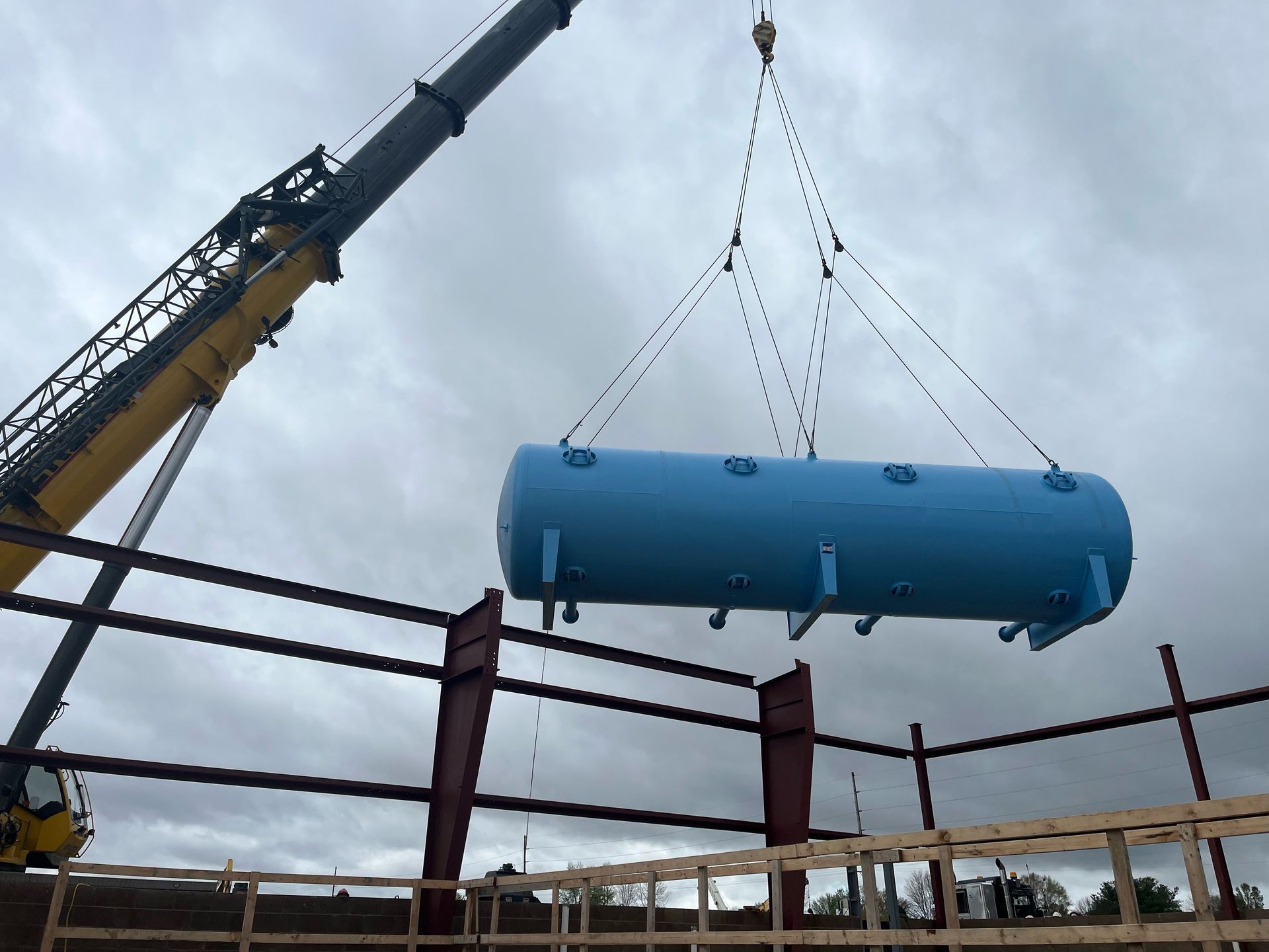 A large blue tank is being lifted by a crane.